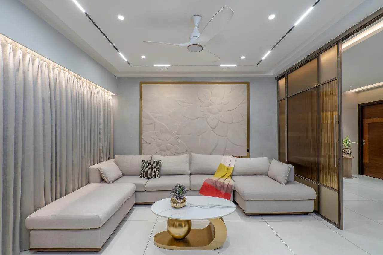 A living room in pale stone and oak, opening to a glazed balcony